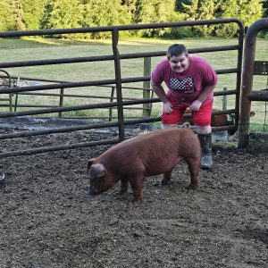 James with his hog, Dodge in a livestock pen.