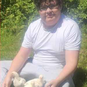 Jake Erickson with his 3 fryer chickens: Curry, Rotisserie, and BBQ sitting on a grass lawn.