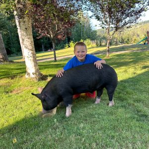 Brody with his hog, Tank under a tree.