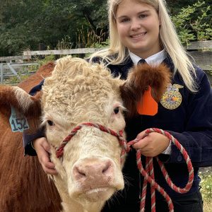 Samantha smiling with her arm around her steer, Georgie.