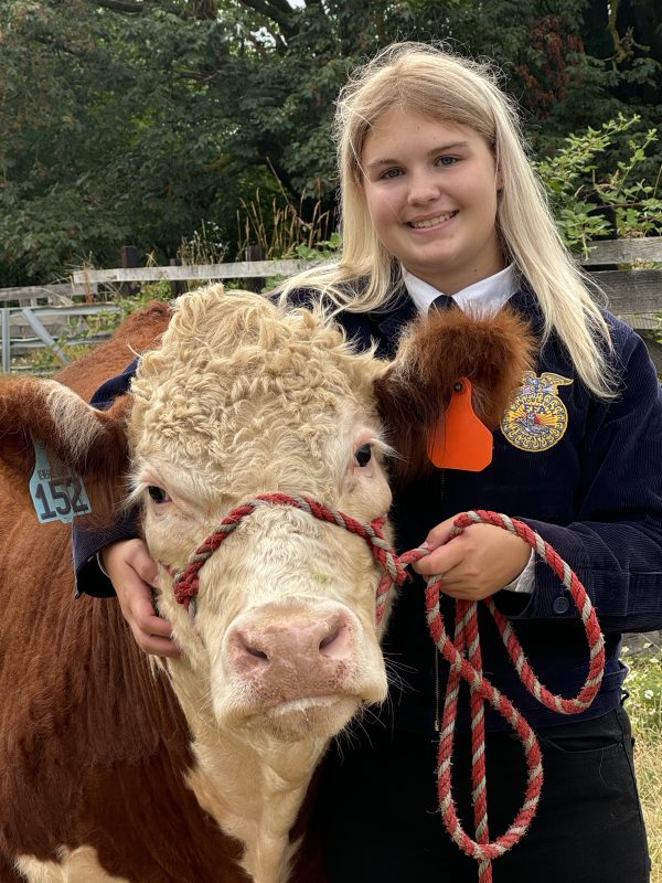 Samantha smiling with her arm around her steer, Georgie.